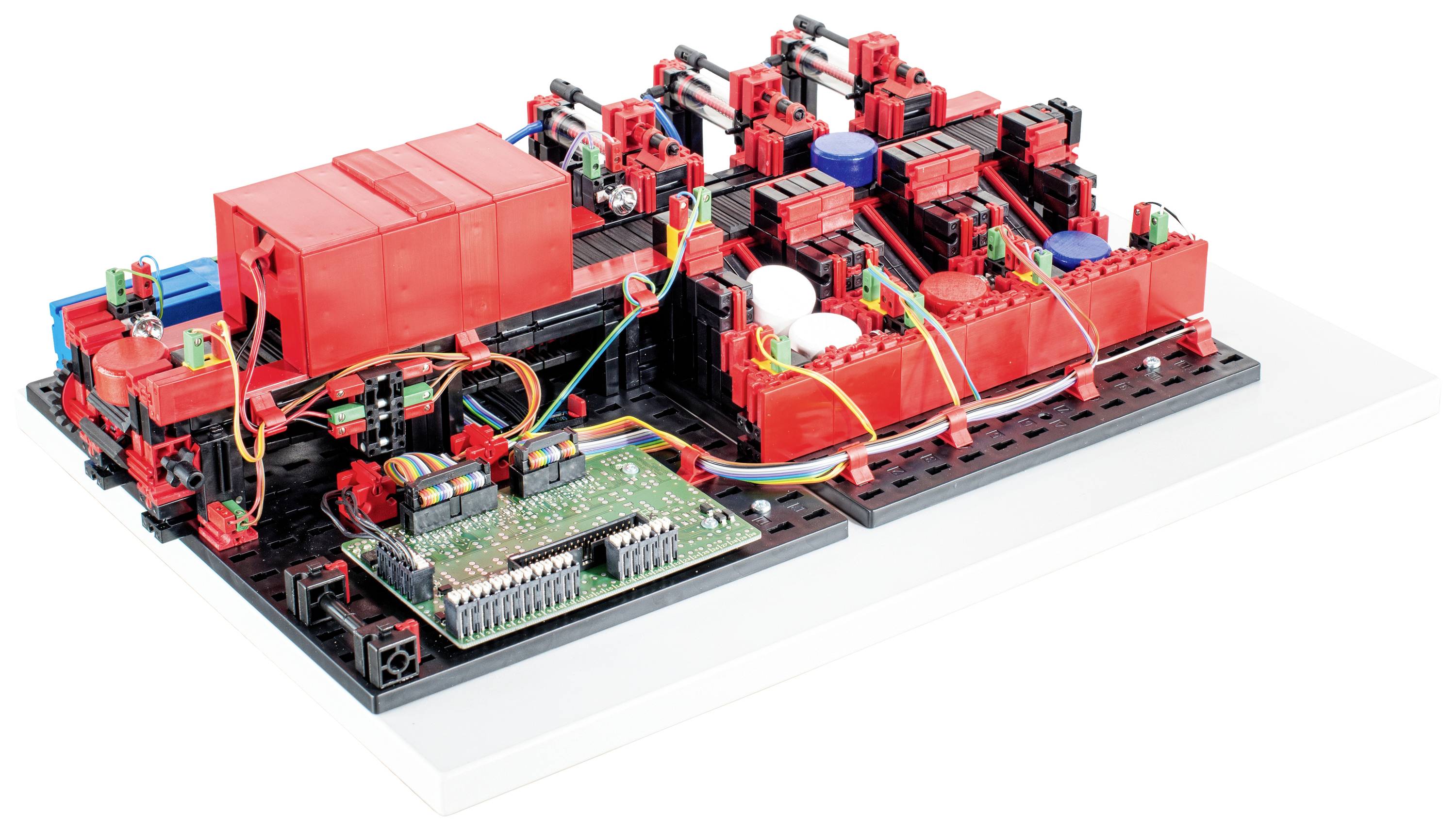 Un modèle d'installation avec des composants rouges et noirs sur une base blanche, reliés par une carte de circuit imprimé verte.