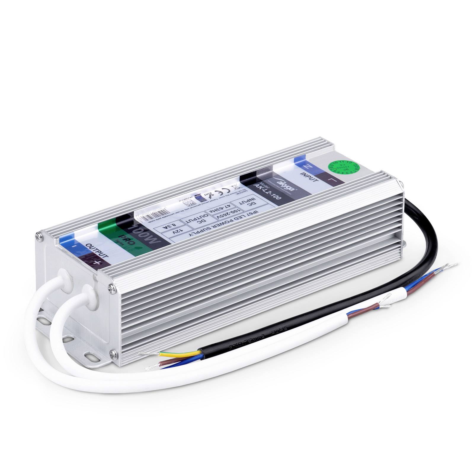 Un transformateur électrique avec des bornes et des câbles marqués, posé sur une surface blanche.