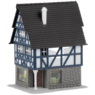Maquette d'une maison à colombages avec des poutres bleu et blanc et des détails en pierre grise, avec des vitrines au rez-de-chaussée.