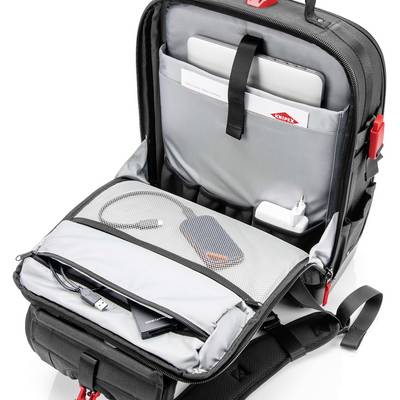 Un sac à dos noir ouvert montre des compartiments intérieurs avec un ordinateur portable, un disque dur et un câble de chargement. Idéal pour les voyages.