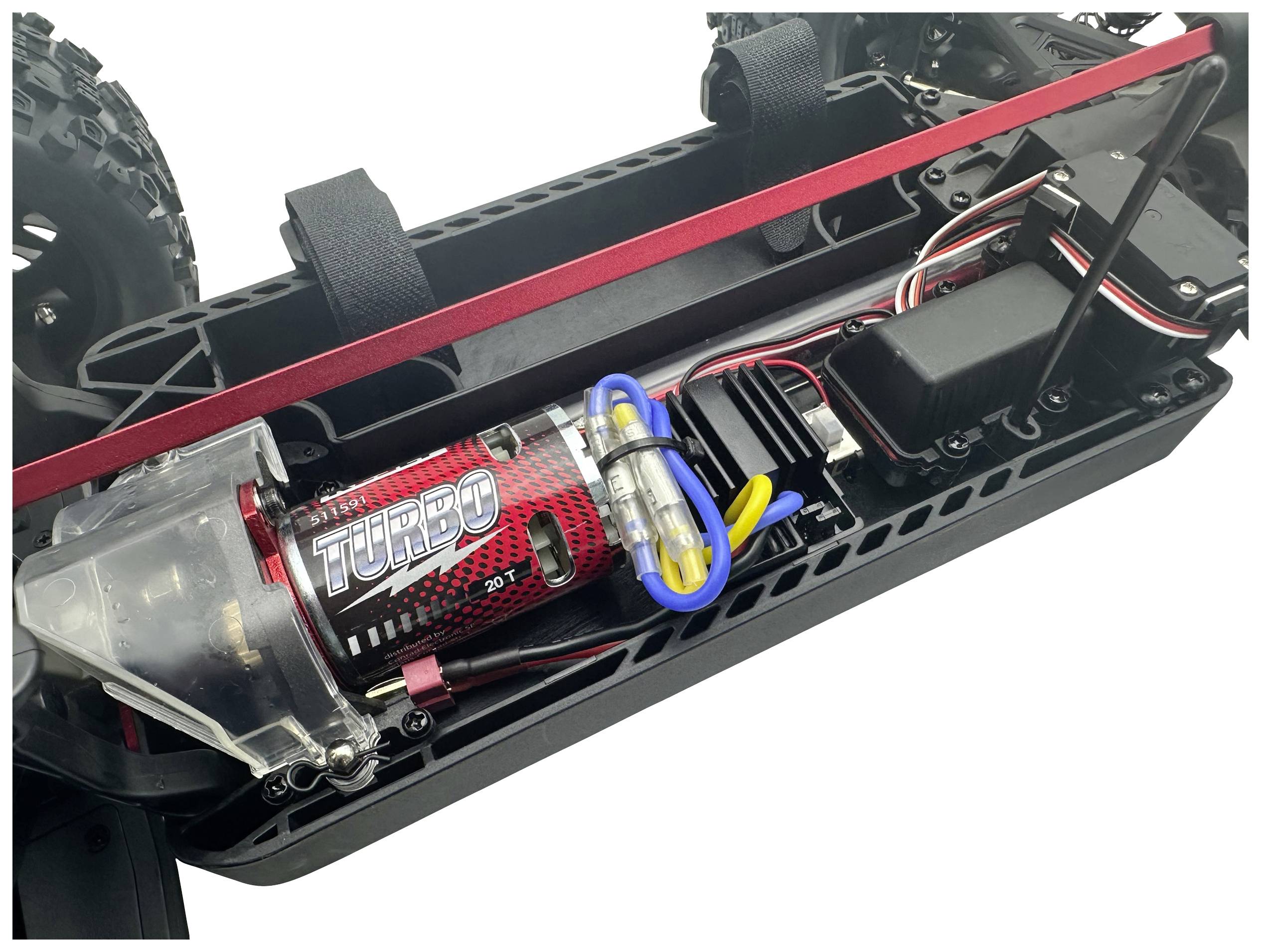 Gros plan d'une voiture télécommandée avec châssis ouvert, révélant le moteur portant l'inscription 'Turbo' et ses composants électroniques.