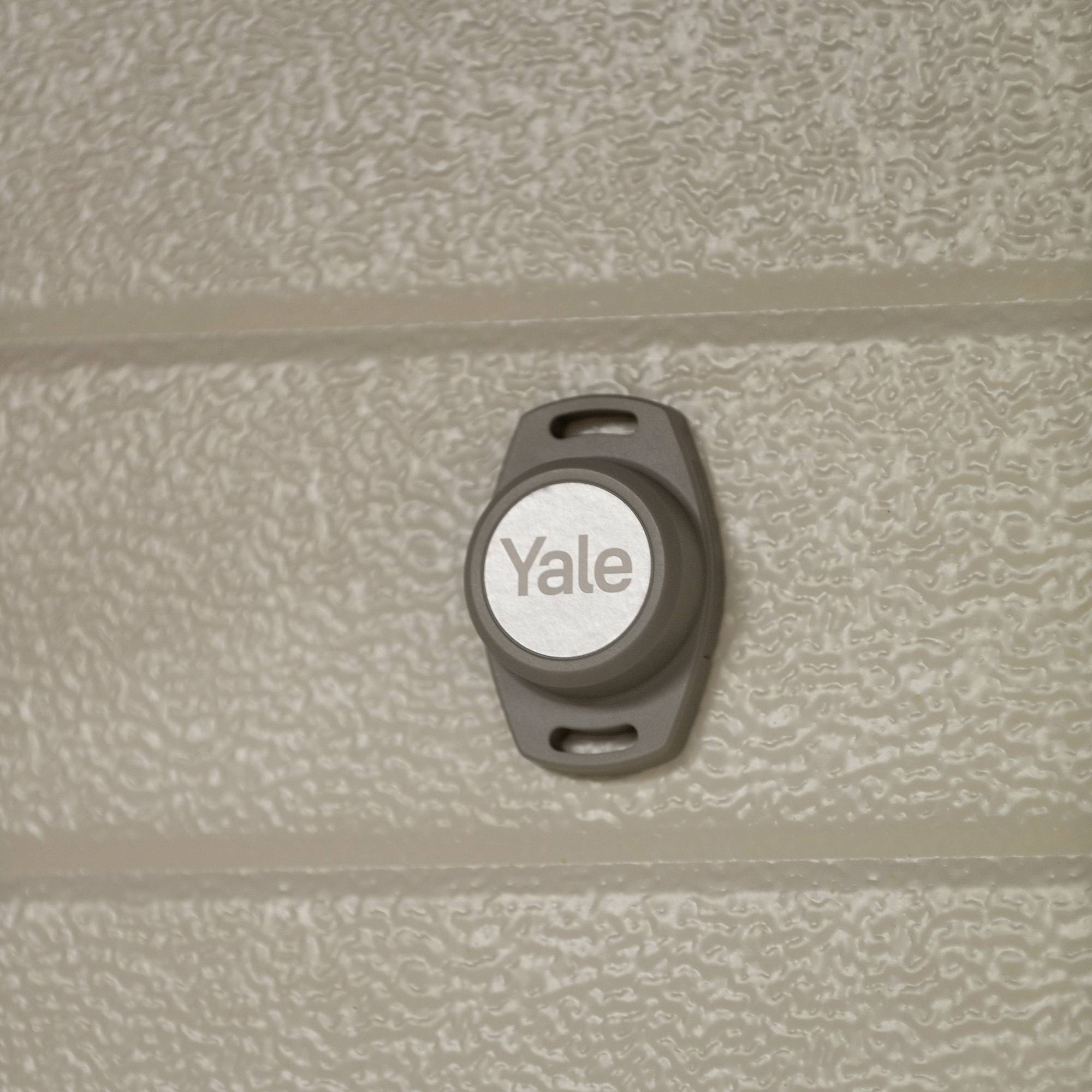 Un dispositif rond et gris de Yale est fixé à un mur structuré.