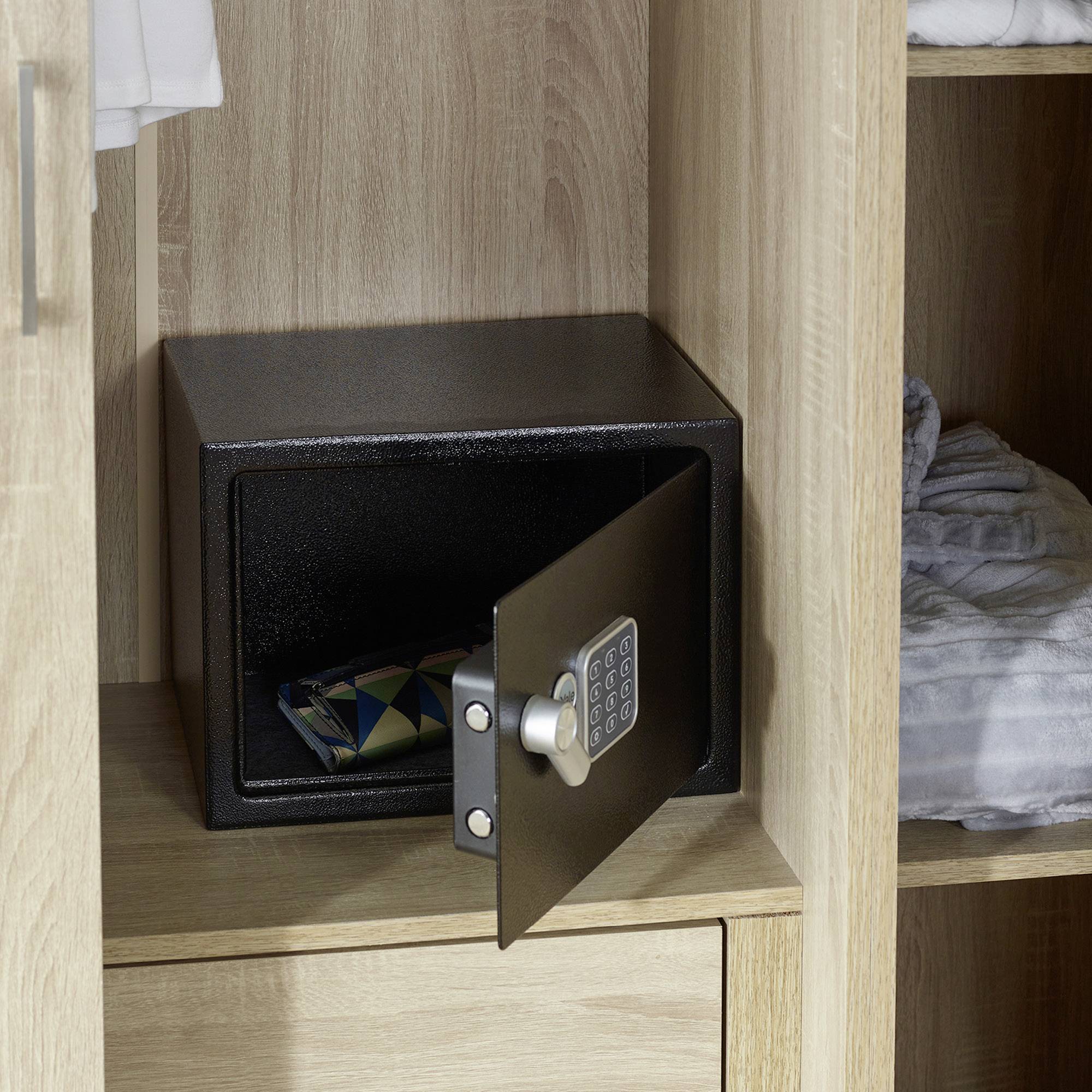 Un coffre-fort ouvert dans un placard, à l'intérieur duquel se trouve un portefeuille. Des vêtements sont visibles en arrière-plan.