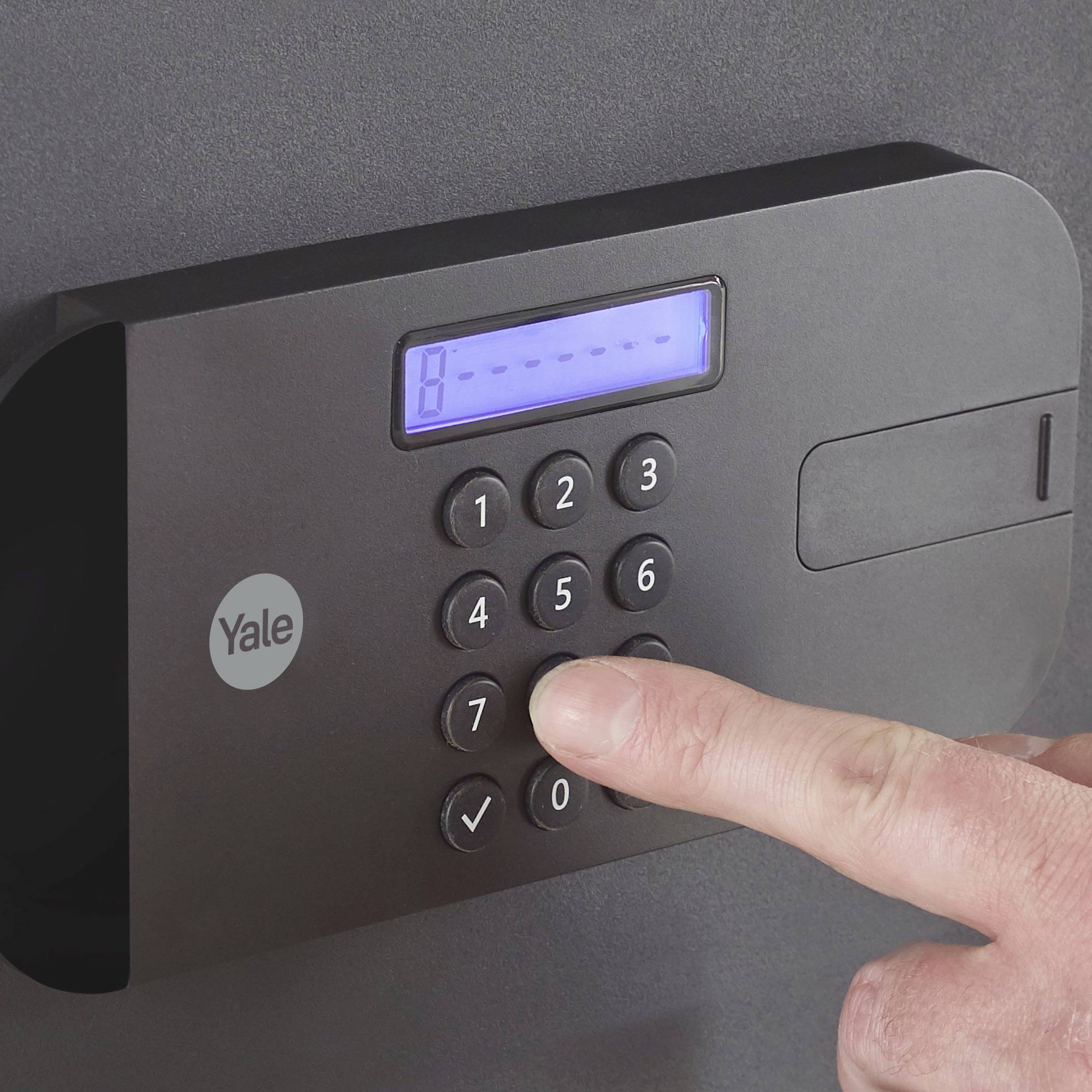 Une main appuie sur le clavier numérique d'un coffre-fort électronique pour saisir un code.