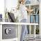 Une femme range des dossiers dans une étagère dans un bureau moderne, avec un ordinateur portable sur la table et un coffre-fort fixé sur le côté de la table.