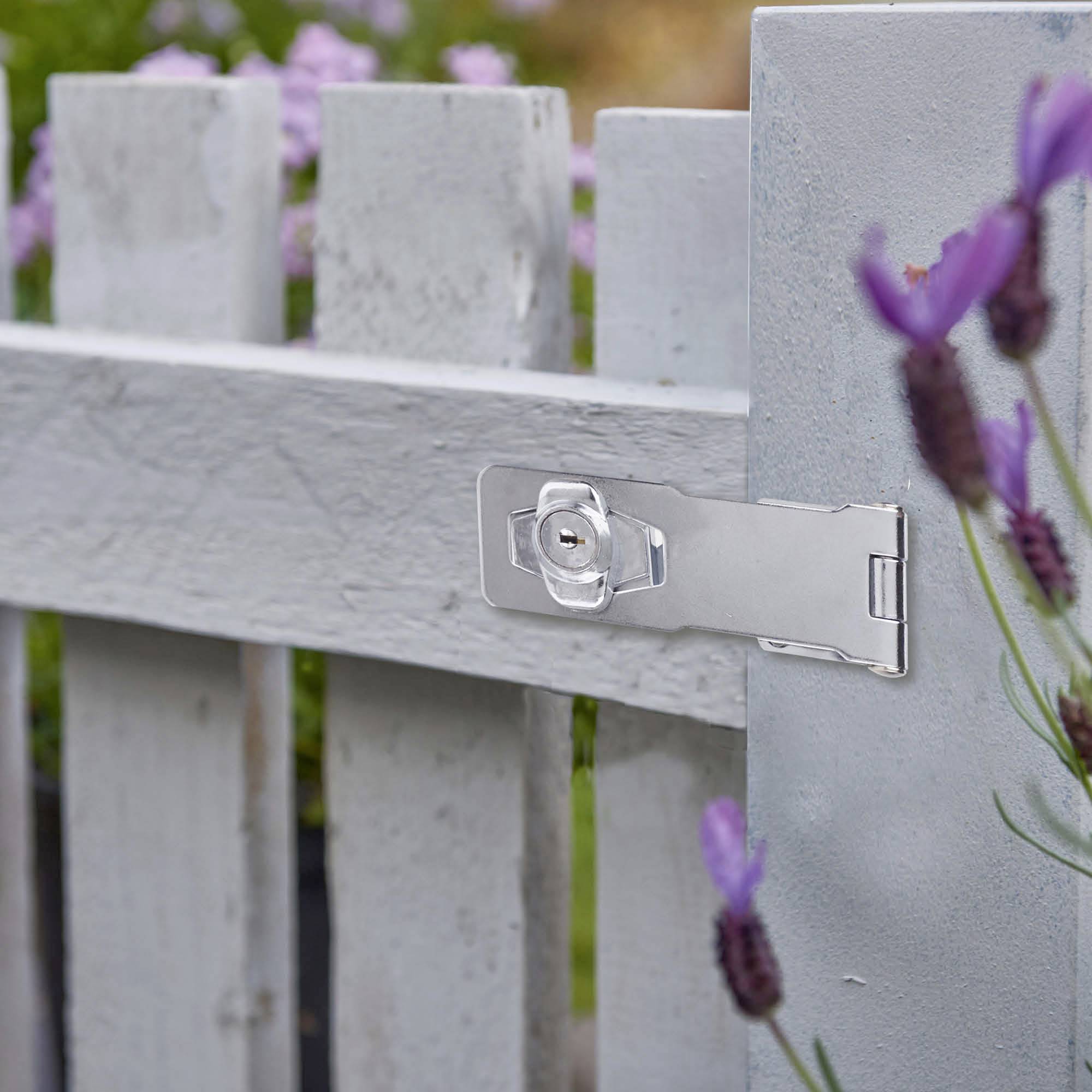 Une porte en bois grise avec une serrure argentée, entourée de fleurs de lavande violettes dans le jardin.