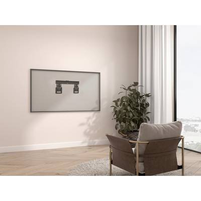 Un salon aménagé de manière minimaliste avec un cadre photo vide accroché au mur, un fauteuil, un tapis et une plante.