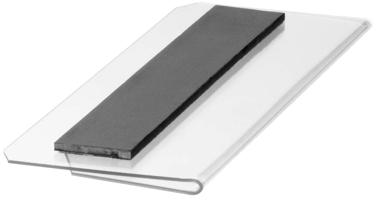 Un morceau de plastique transparent avec une bande rectangulaire noire au-dessus, photographié en angle.