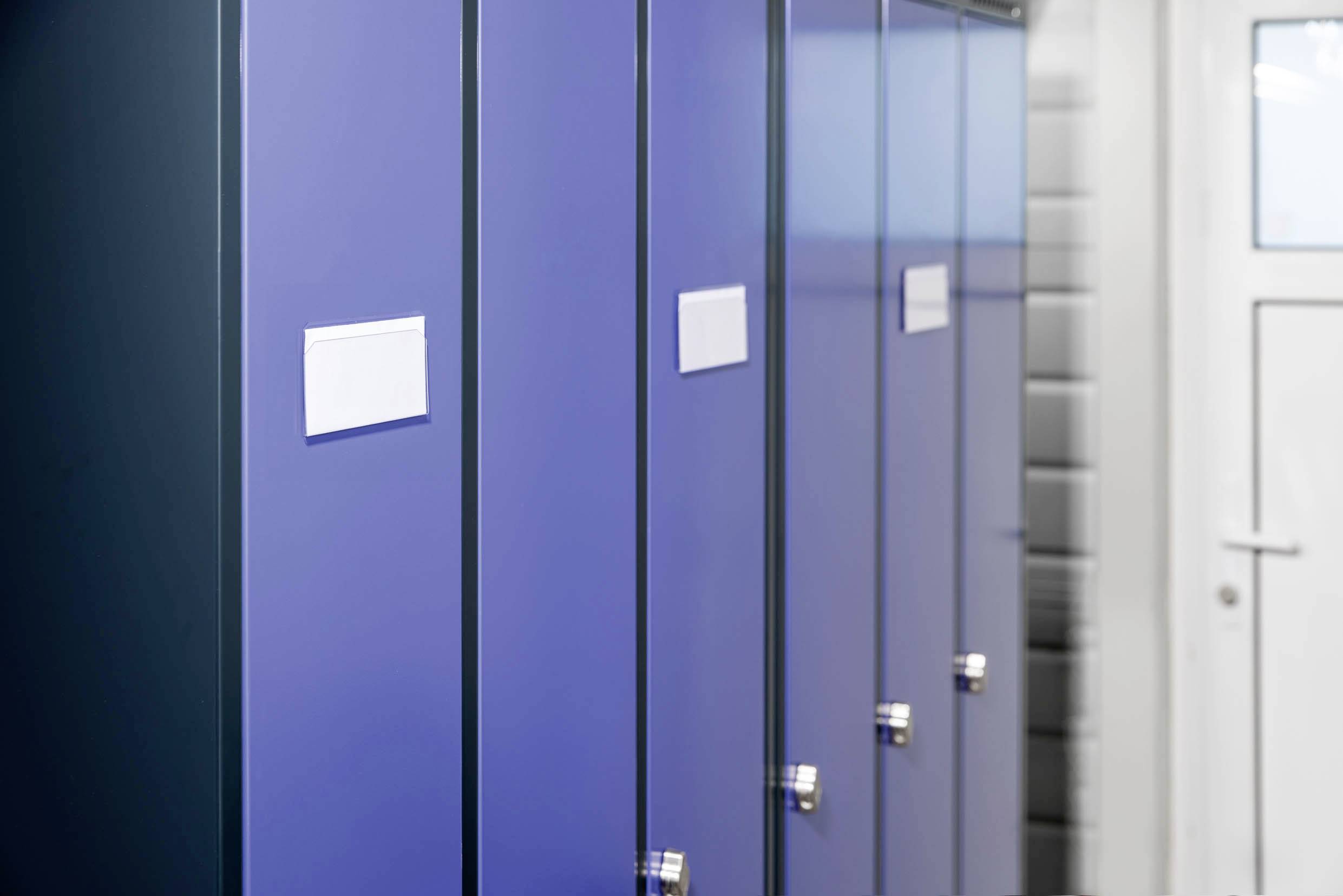 Des casiers bleus alignés à côté d'une porte blanche dans un couloir.