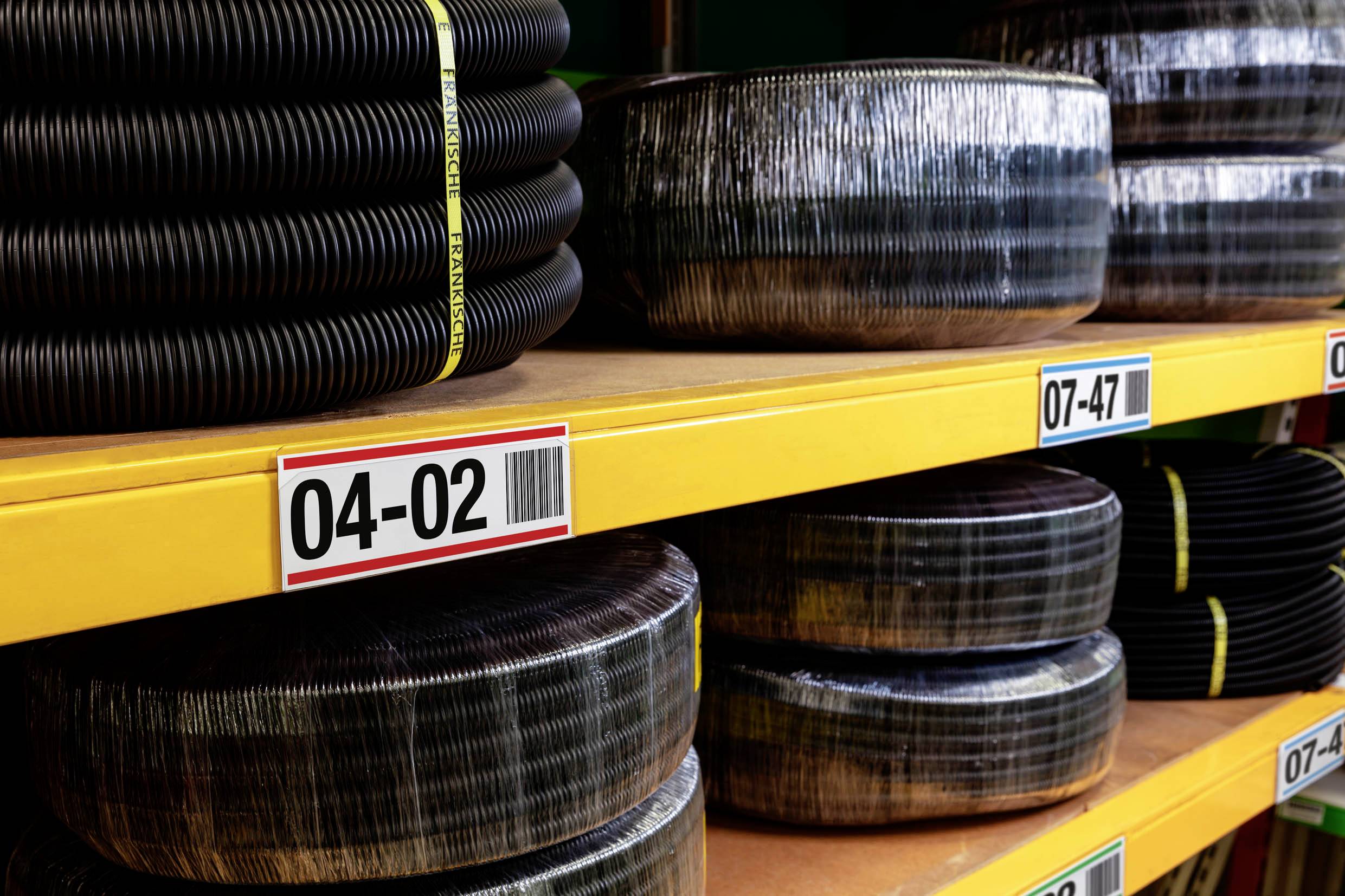 Entreposez des rouleaux de câble noir, numérotés '04-02' et '07-47', dans un entrepôt.