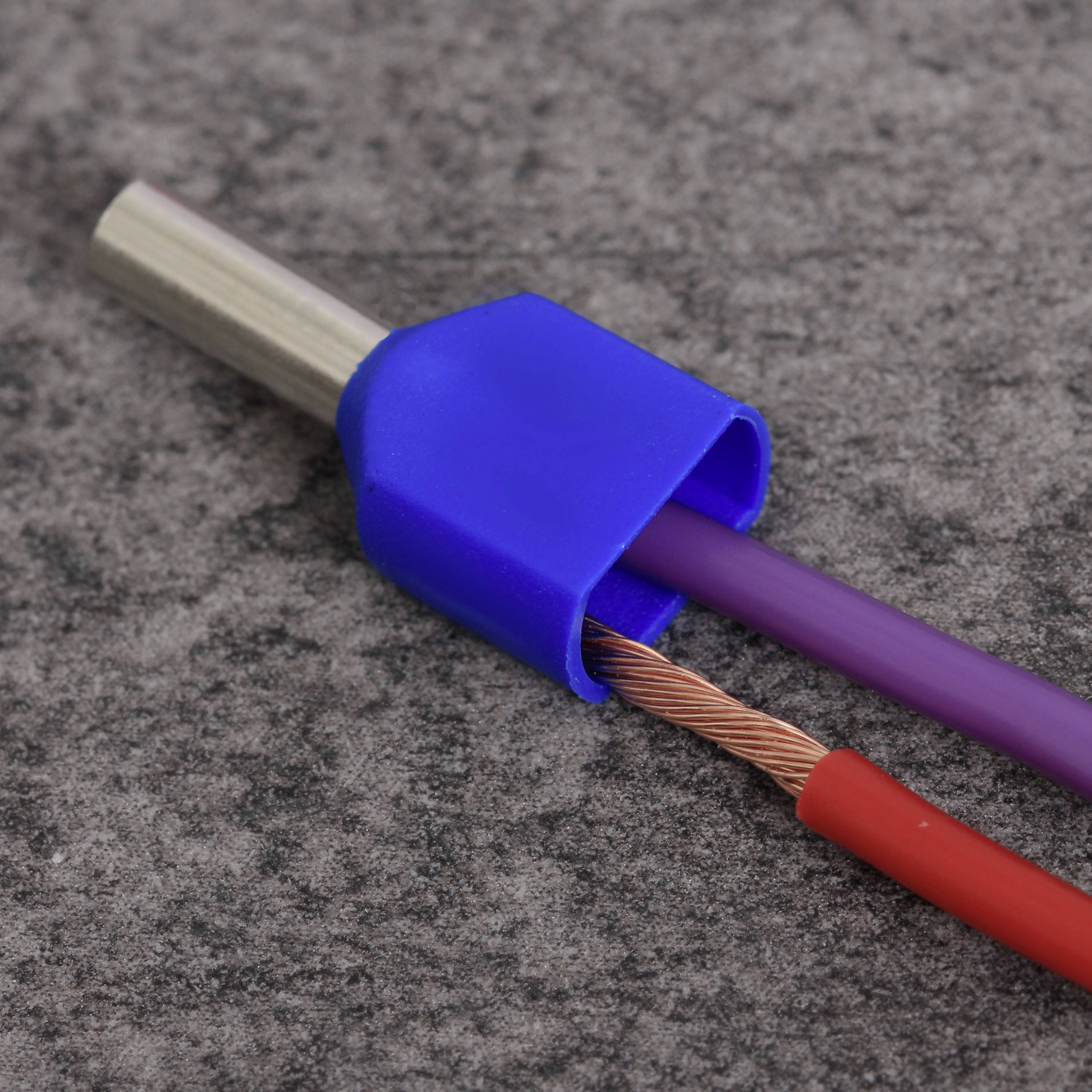 Câble électrique avec une connexion en plastique bleue, révélant une extrémité de fil de cuivre dénudée, sur un fond gris.