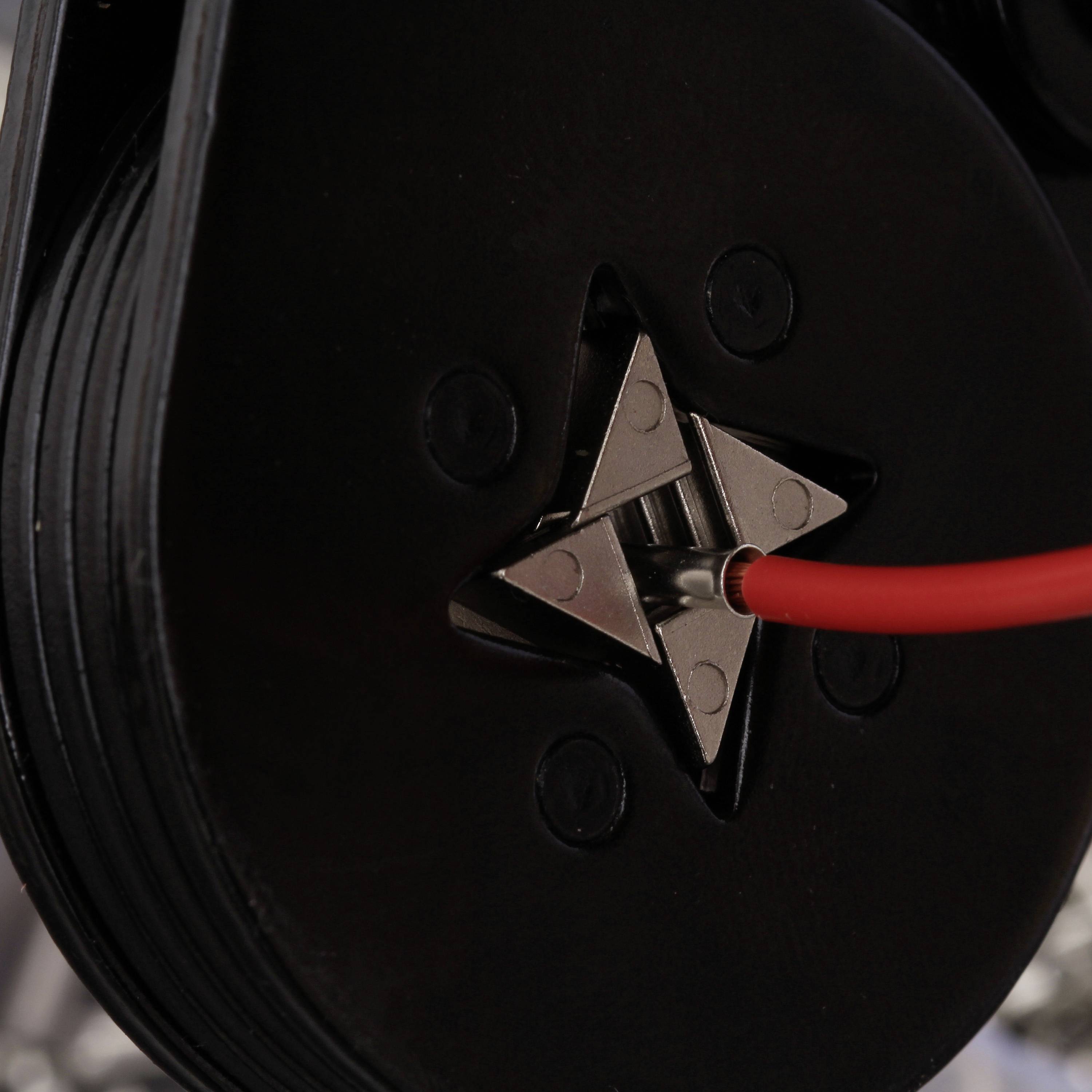 Gros plan d'un câble rouge enfoncé dans un élément de connexion noir en forme d'étoile.