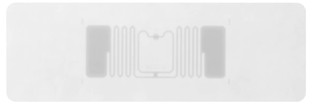 Une étiquette RFID sous forme d'autocollant, composée d'une petite puce au centre et d'une antenne environnante, sur fond gris.