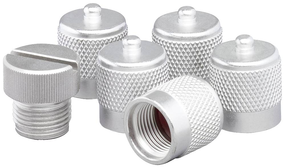 Six capuchons en métal argenté, disposés en partie debout et en partie couchés, avec des surfaces striées. Un capuchon présente un filetage avec une fente.