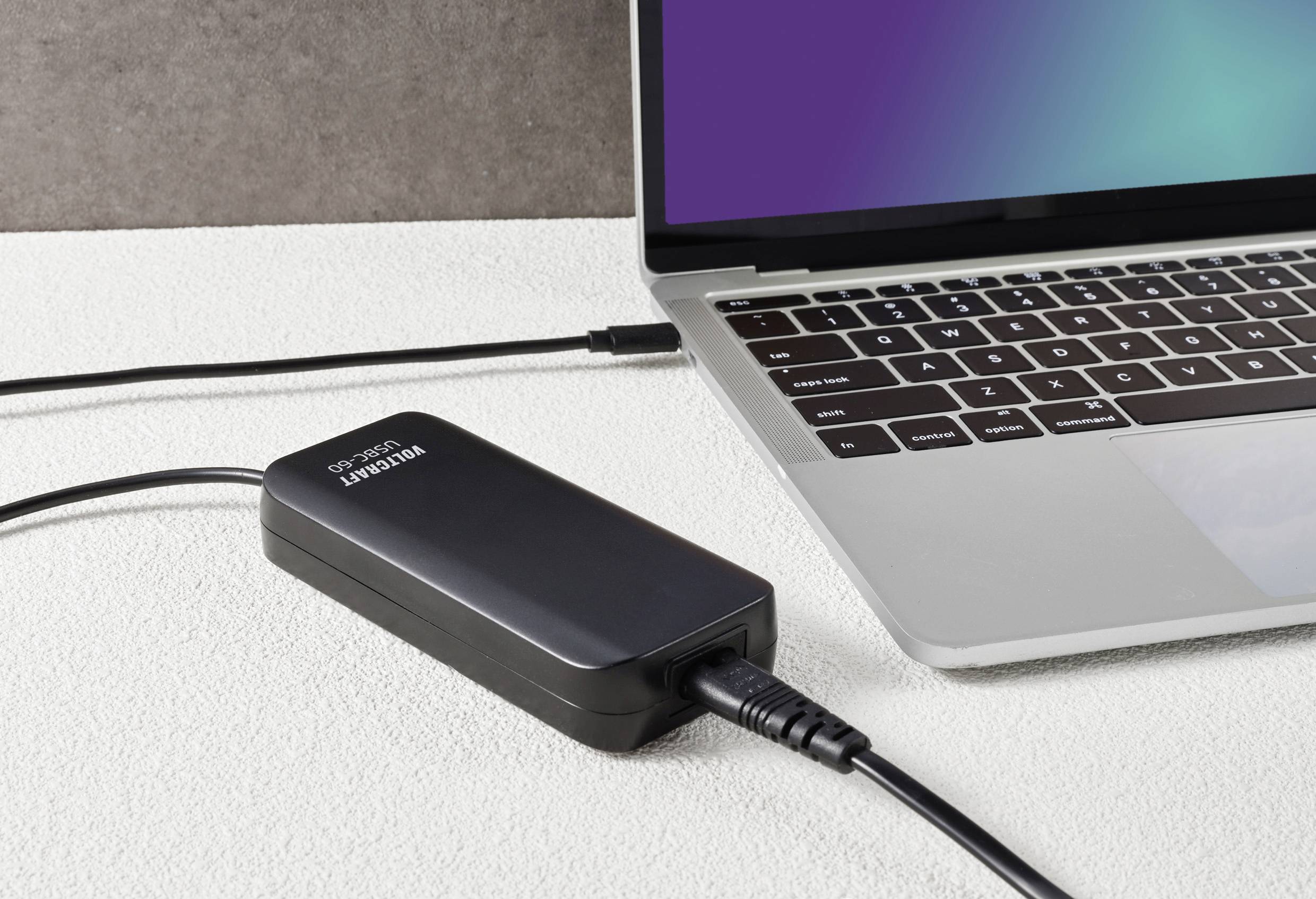 Un ordinateur portable est connecté à un chargeur portable qui repose sur une table. L'écran de l'ordinateur portable est partiellement visible.