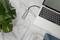 Un ordinateur portable est posé sur une table en marbre et connecté via un hub USB avec plusieurs câbles. À côté se trouve une plante verte.