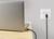 Un ordinateur portable est en charge sur un chargeur noir branché à une prise électrique blanche murale, posé sur une table en bois.