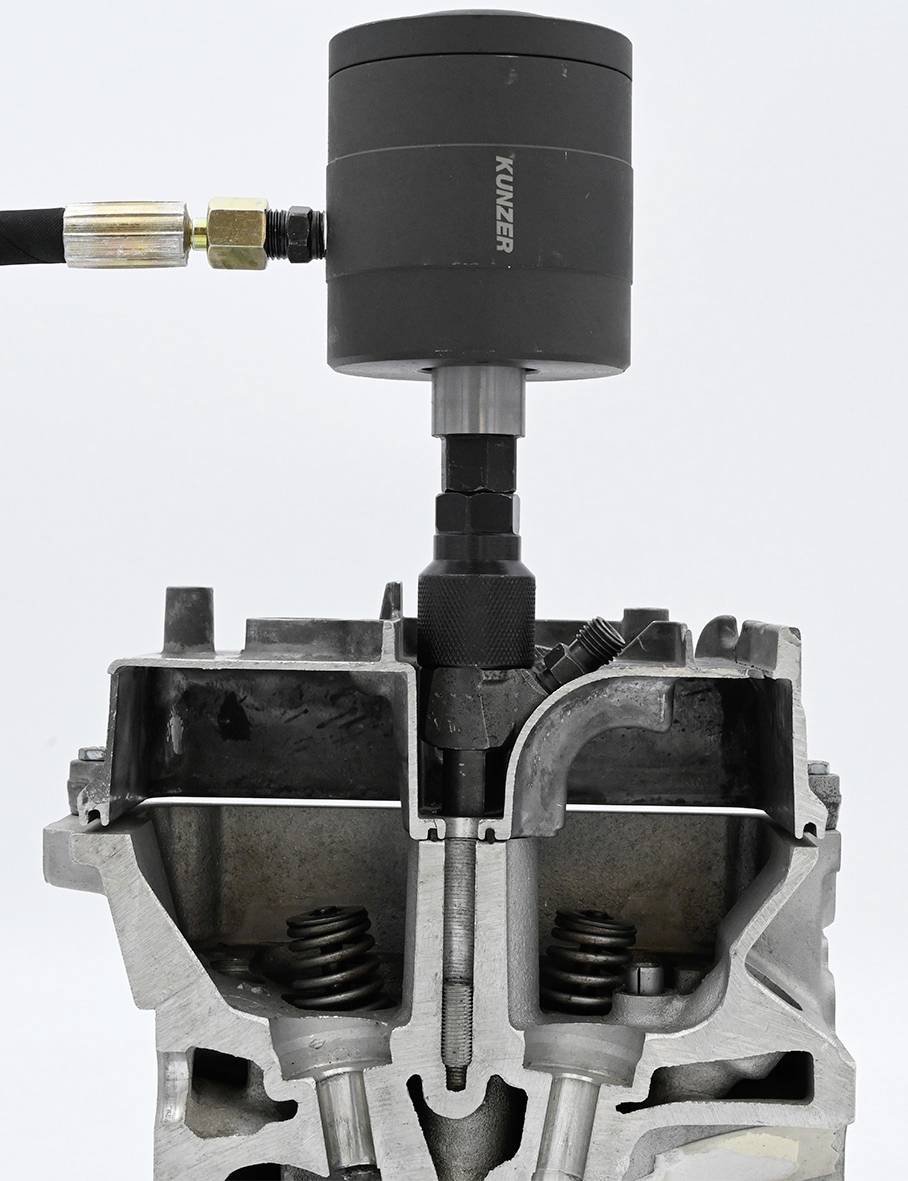 Un outil de vérification de la compression des cylindres est connecté à un cylindre de moteur ouvert. Adaptateurs et ressorts visibles.