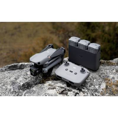 'Drone grise sur un rocher avec télécommande et étui de batterie. Arrière-plan flou aux couleurs naturelles.'