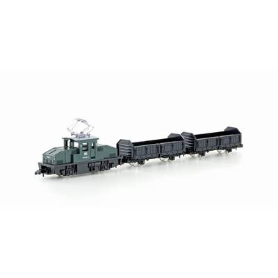 Un train miniature avec une locomotive verte et trois wagons de marchandises ouverts noirs à l'échelle sur un fond blanc.