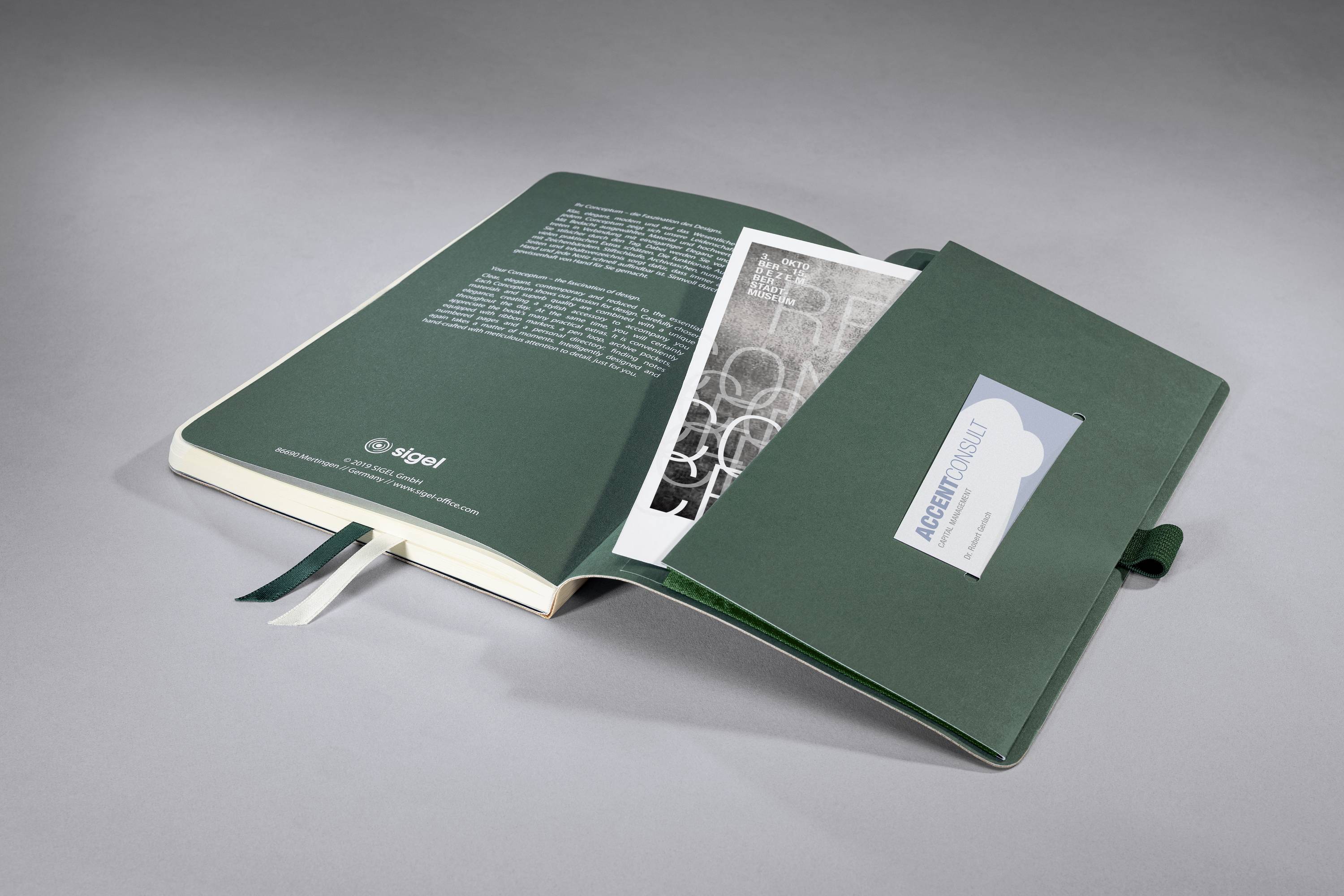 Un carnet vert est ouvert sur une table. À côté, on peut voir une enveloppe ouverte portant l'inscription « Notes d'architecture ».