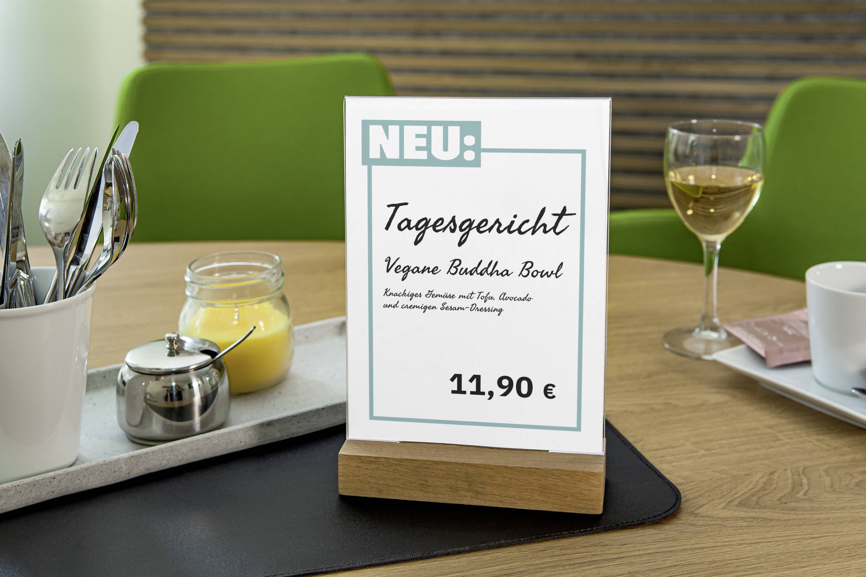 Chevalet de table au restaurant présentant le plat du jour : 'Buddha Bowl végane' à 11,90 EUR. Au fond, du vin et des couverts.