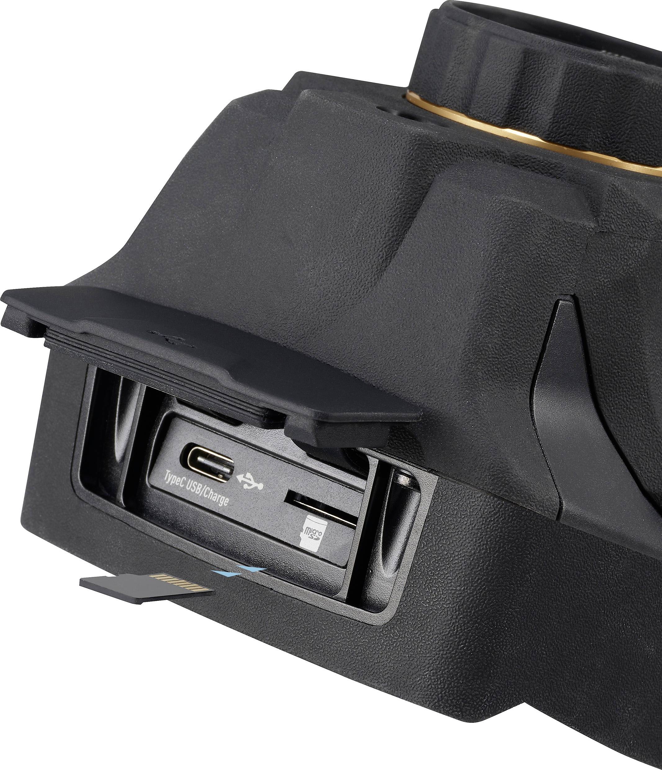 Caméra noire avec compartiment ouvert montrant les ports USB-C et Micro-USB. Une puce de mémoire est en cours d'insertion.