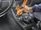 Une personne nettoie la console centrale d'une voiture à l'aide d'un outil multifonction orange à batterie.
