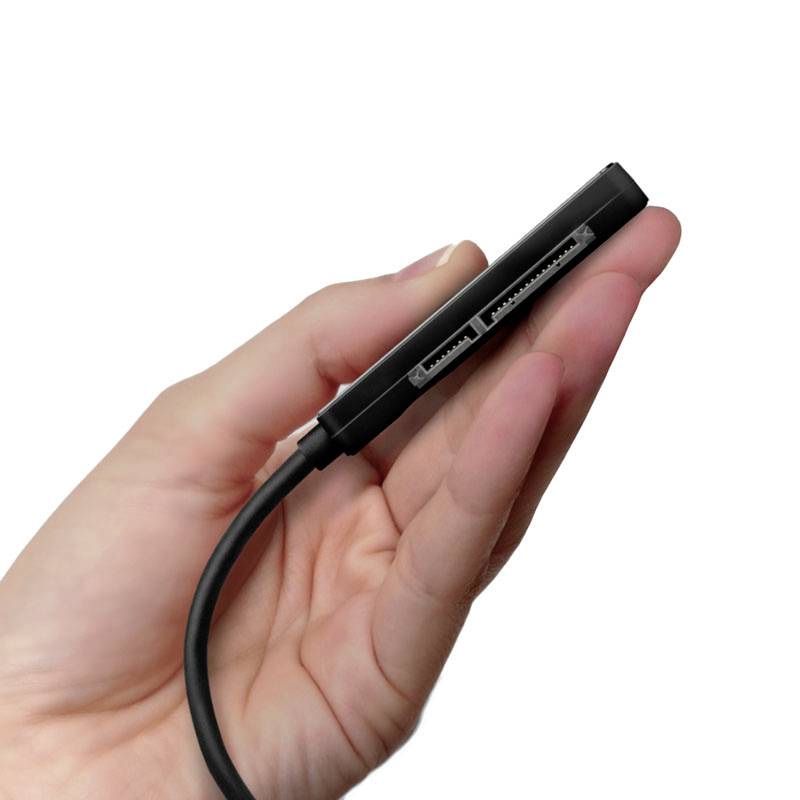 Une main tient un adaptateur SATA.