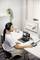 Une femme est assise à un bureau, portant des écouteurs et un microphone, devant un ordinateur portable et un moniteur sur lequel est affiché 'Art Forum'.