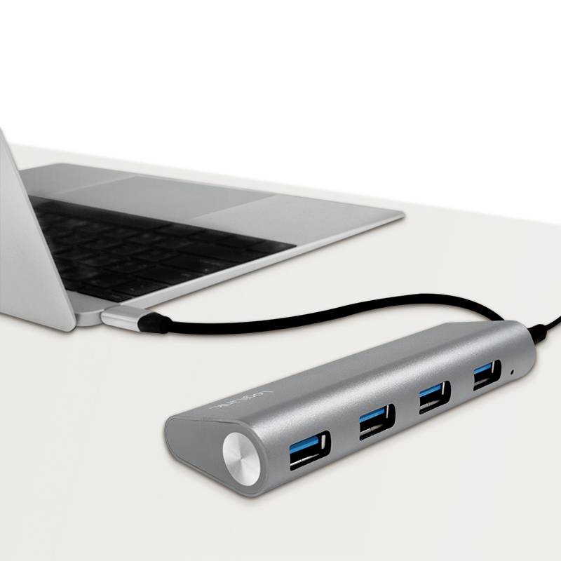 Un ordinateur portable est connecté à un hub USB offrant quatre ports USB. Le hub est de couleur argent et est placé sur une table.