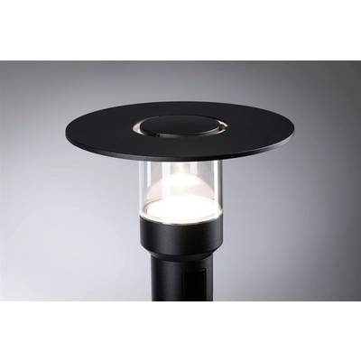 Lampadaire noir moderne avec un cylindre en verre transparent et un abat-jour rond et plat, éclairant un espace minimaliste.