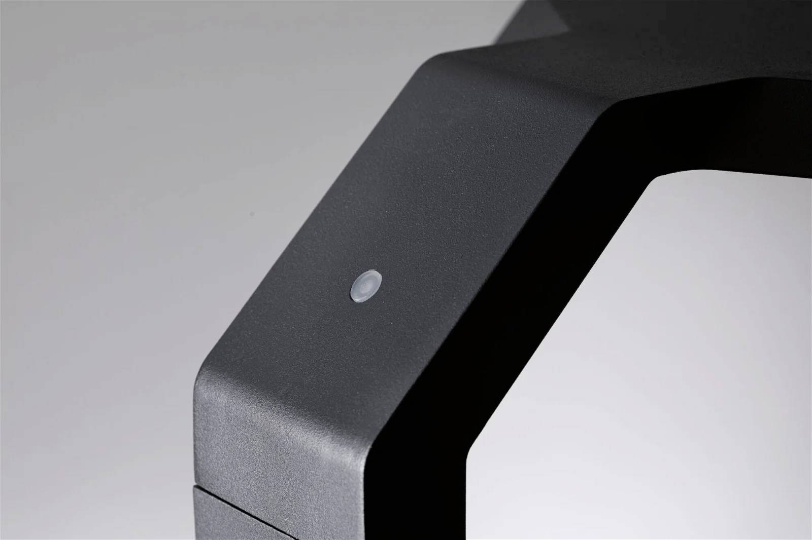 Support de lampe moderne noir avec des bords arrondis et un petit capteur circulaire sur le dessus.