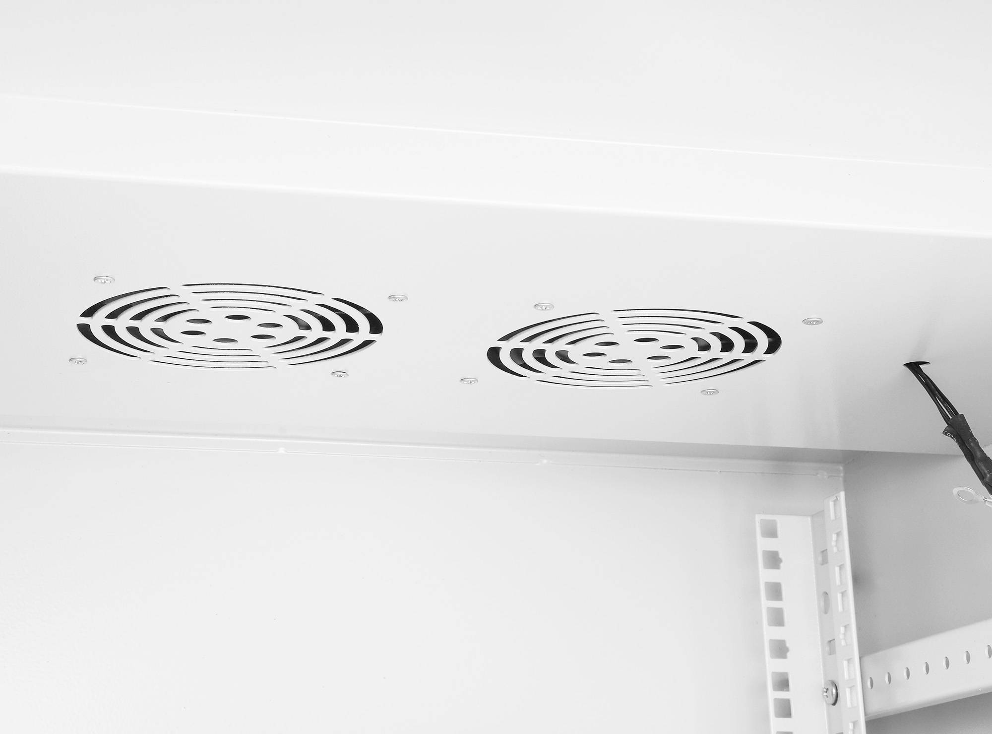 Surface blanche avec deux grilles de ventilation rondes et un câble pendant sur le côté.