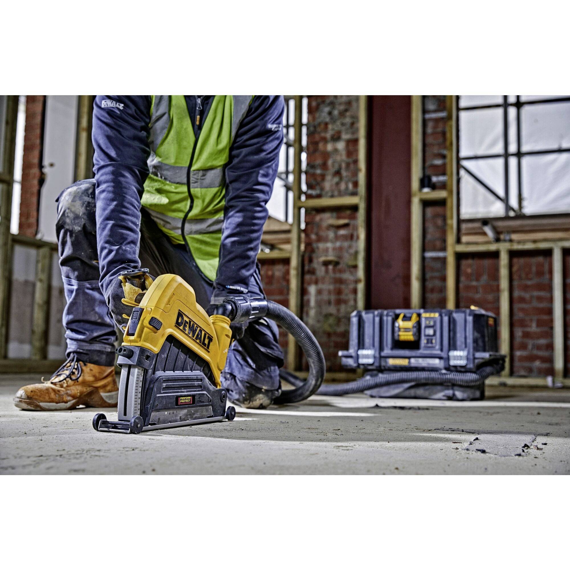 Un ouvrier en tenue de travail utilise une scie électrique portative sur un chantier de construction ; une boîte à outils est visible en arrière-plan.