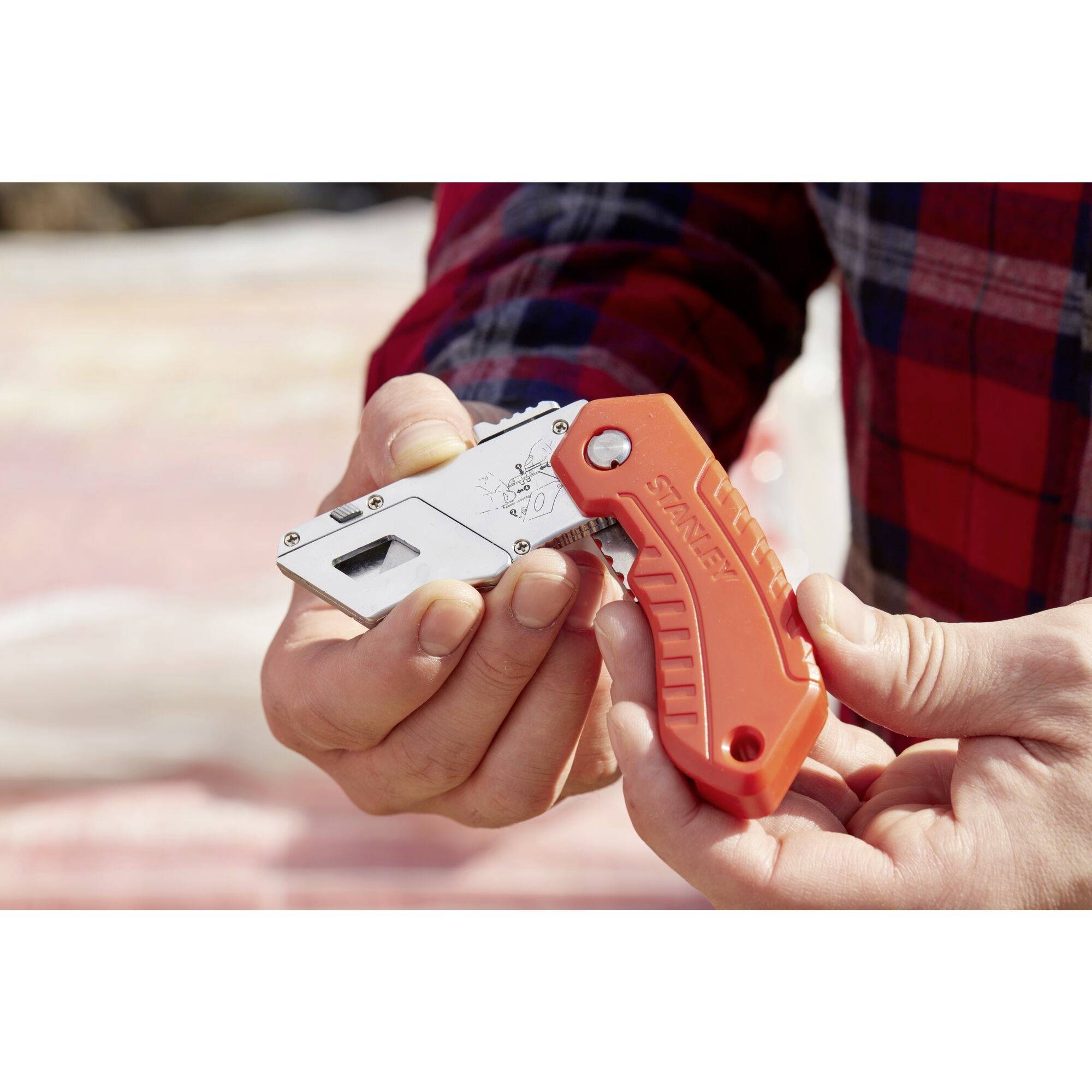 Une personne tient un couteau multifonction orange dans sa main. Le couteau a une lame dépliée et la marque est visible.