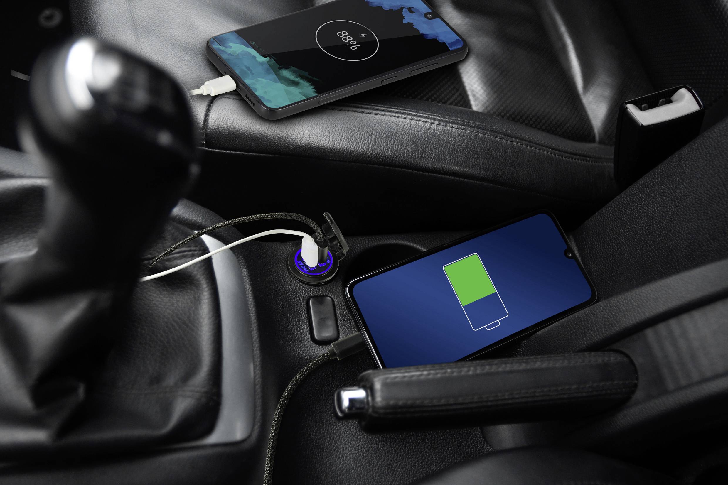 Deux smartphones en charge dans la voiture : l'un est posé sur la console centrale, l'autre sur le siège passager, tous deux affichant des indicateurs de charge.