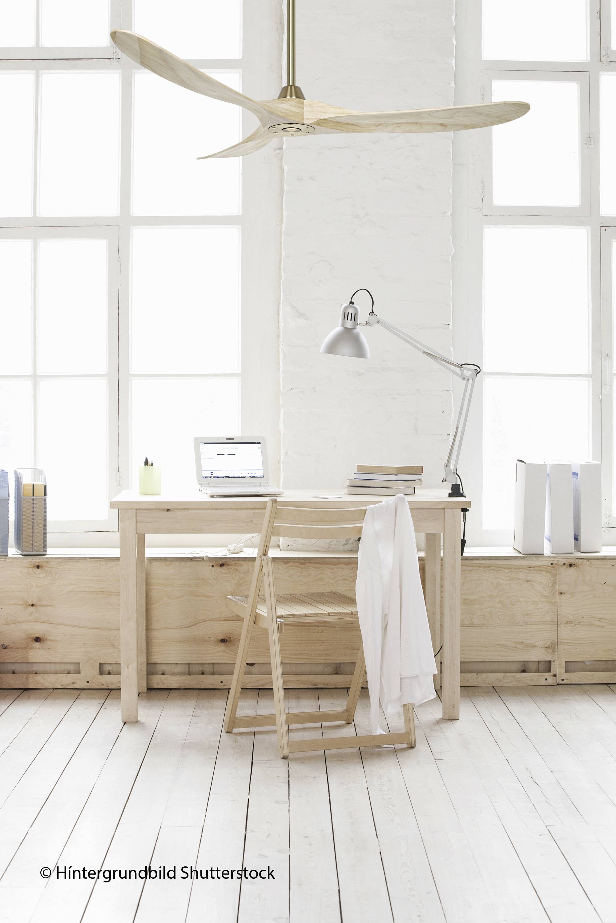 Un espace de travail aménagé de manière minimaliste avec une table en bois, un ordinateur portable, une lampe, une chaise en bois et de grandes fenêtres en arrière-plan.