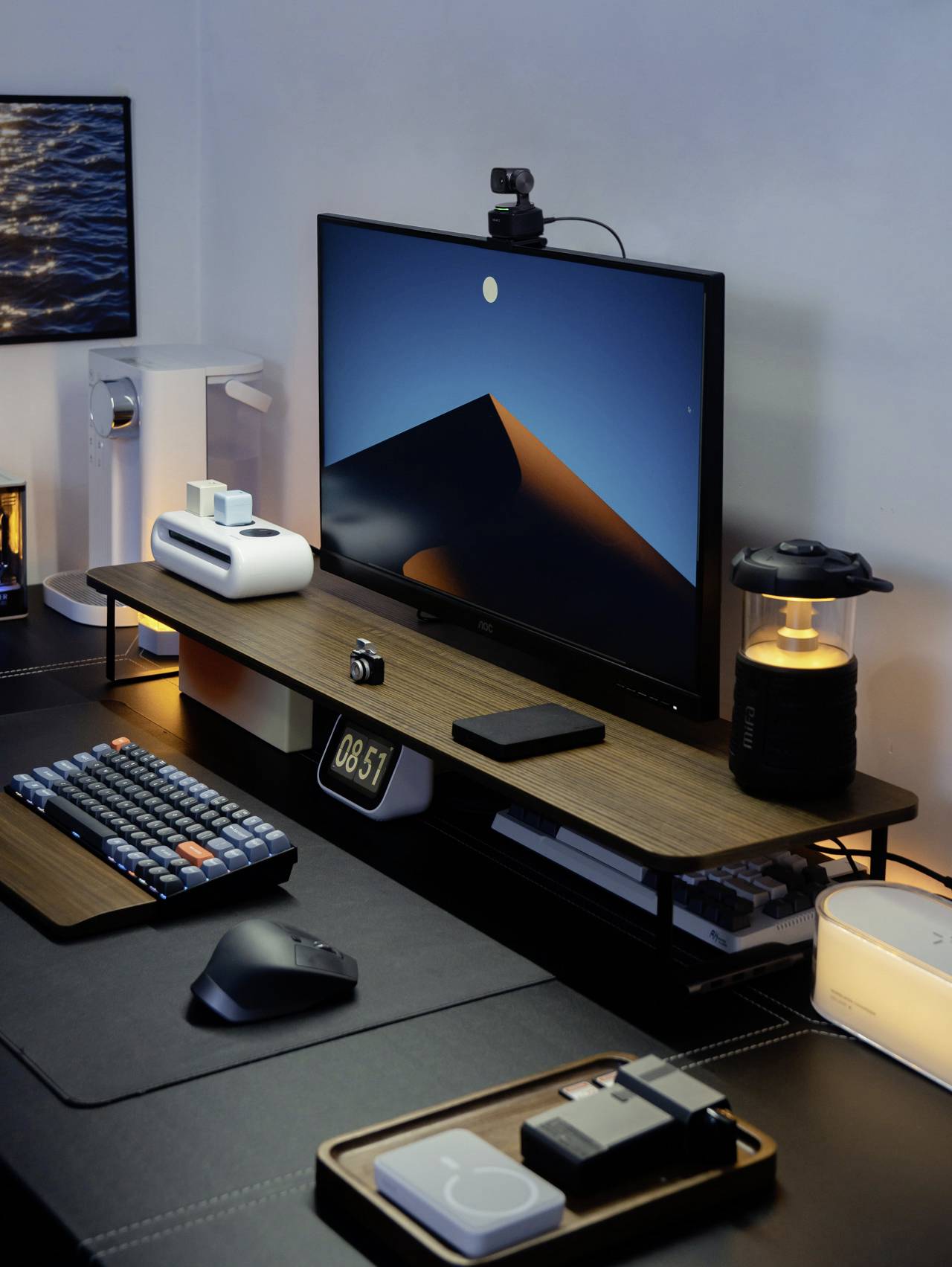 Bureau d'ordinateur moderne avec moniteur, clavier, souris, smartphone et haut-parleurs. L'écran affiche un motif désertique de nuit.