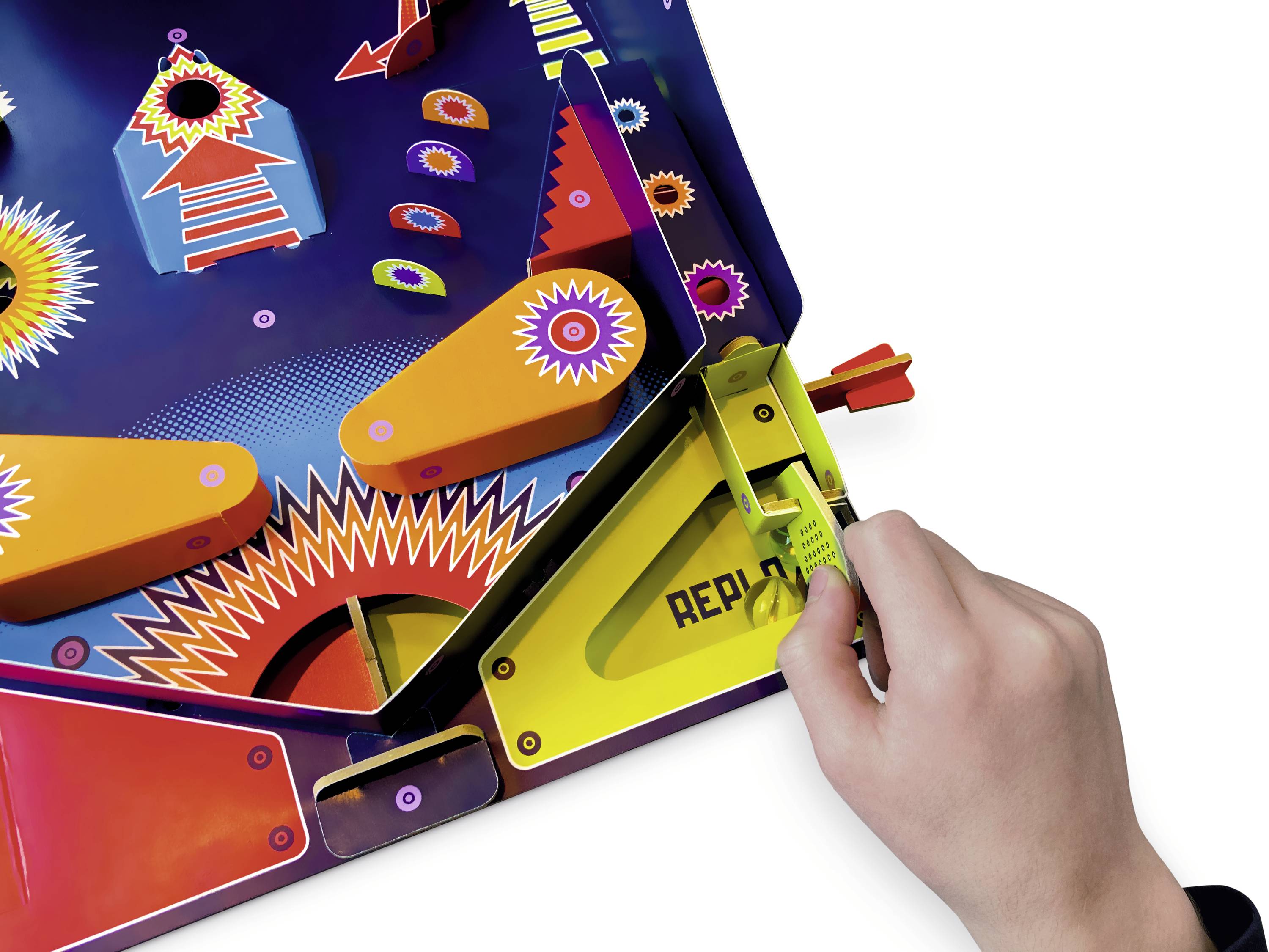 Une main tire le levier d'une machine à flipper colorée. Des motifs graphiques lumineux et chatoyants décorent la surface.