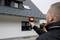 Un homme utilise un appareil de caméra thermique pour inspecter une maison. La caméra révèle les différences de température sur la façade.