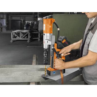 Une personne utilise une perceuse magnétique dans un atelier afin de percer des trous précis dans un support métallique.