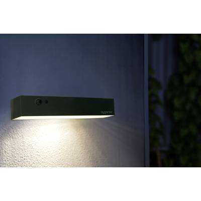 Une lampe rectangulaire et moderne projette une lumière chaleureuse sur un mur.