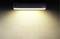 Une lampe murale rectangulaire diffuse une lumière douce et blanc chaud sur un mur beige. Le nom de la marque est dans le coin supérieur droit.