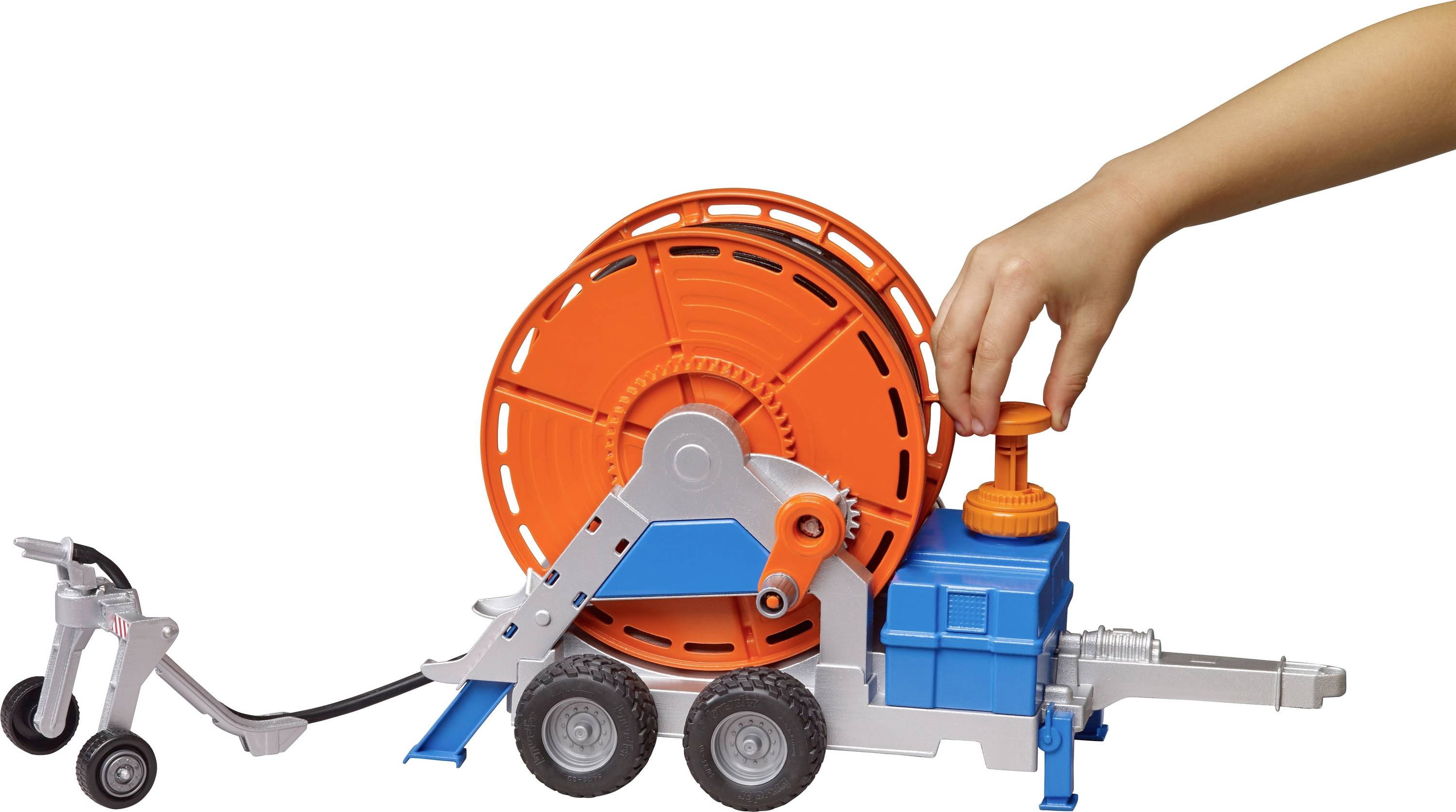 Un enfant manipule un jouet représentant un enrouleur de câble orange monté sur un châssis roulant bleu.