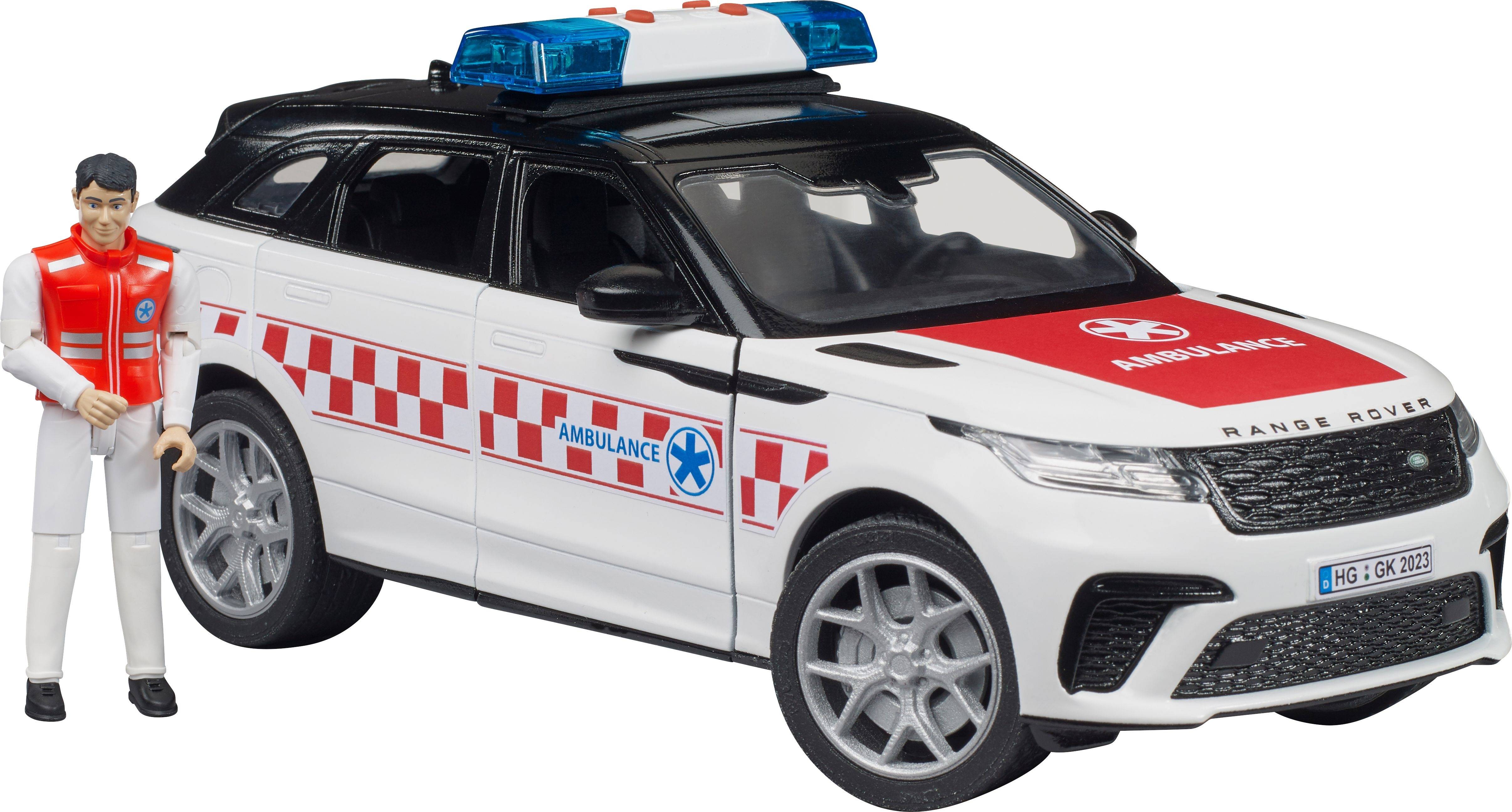 Modèle réduit d'une ambulance avec une peinture rouge et blanche et un gyrophare bleu sur le toit. Une figurine est placée à côté.