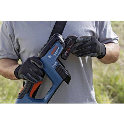 Homme portant un t-shirt gris et des gants noirs, tenant un sécateur à batterie Bosch et une batterie à l'extérieur.