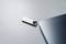 Une clé USB argentée est posée sur une table gris clair à côté d'un ordinateur portable.