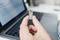 Une personne tient une clé USB devant un ordinateur portable ouvert. L'écran affiche un document texte flou.