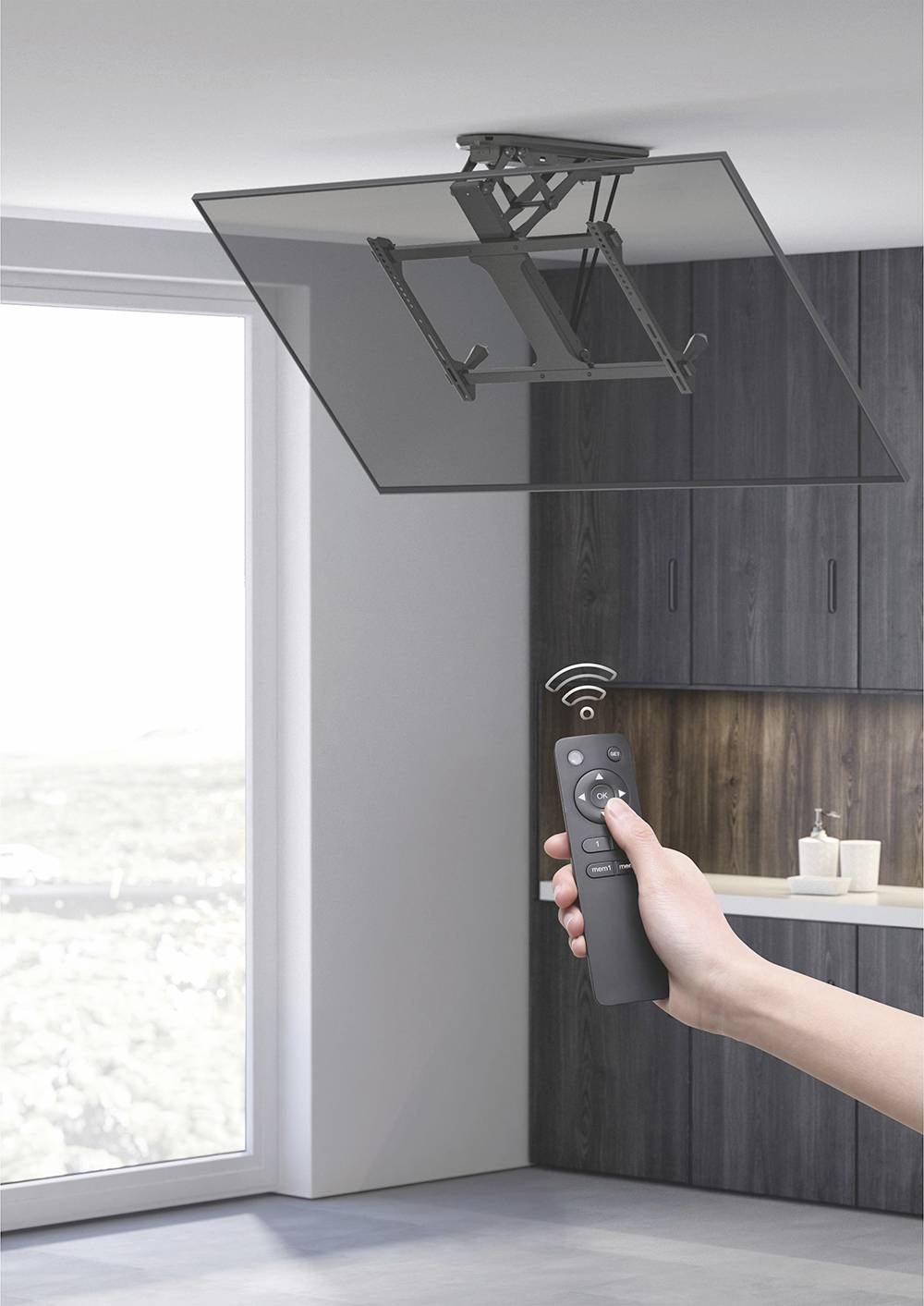 Une main tient une télécommande dans une cuisine pour contrôler un support d'écran fixé au plafond.